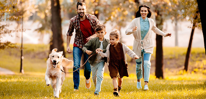 Family running with dog in park